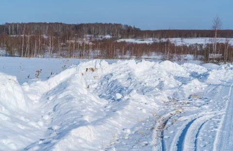 Piles of snow after the work of a tractor to clear rural roads in winter the  Stock Photos