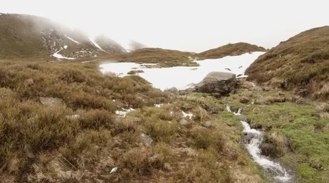 Piles of Snow Turning Into Small Stream on the Mountainside in a Thick Mist Stock Footage 63961335