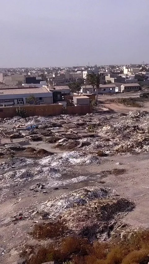 Piles of various waste next to the beach, city buildings in background Stock Footage 230672719