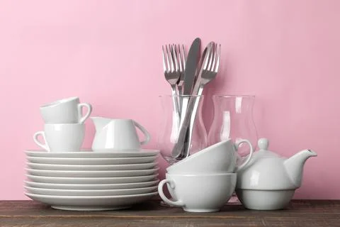 Piles of white ceramic tableware, plates, saucers, cups on a pink background. Stock Photos