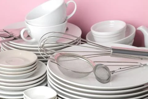 Piles of white ceramic tableware, plates, saucers, cups on a pink background. Stock Photos