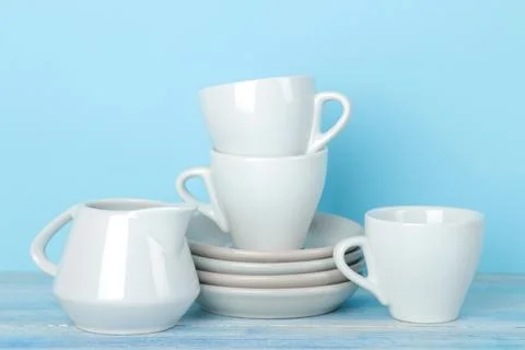 Piles of white ceramic tableware, saucers and cups on a gentle blue backgroun Stock Photos