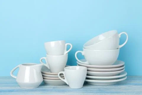 Piles of white ceramic tableware, saucers and cups on a gentle blue backgroun Stock Photos