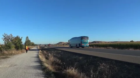 Pilgrim carrying a backpack in the back, going on a country road paved border  Stock Footage 59842093