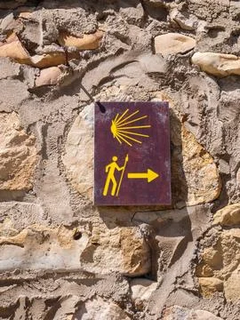 Pilgrimage trail marker on stone wall with scallop shell symbol Stock Photos