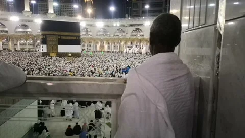 Pilgrims pray while looking at the Kaaba while other pilgrims surround the Kaaba Stock Footage 130228562