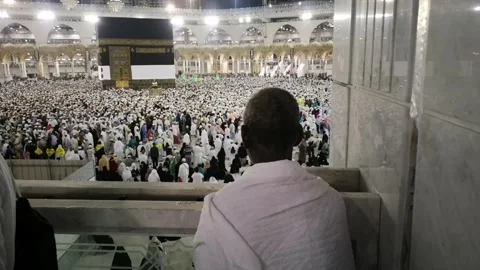 Pilgrims pray while looking at the Kaaba while other pilgrims surround the Kaaba Stock Footage 130228862
