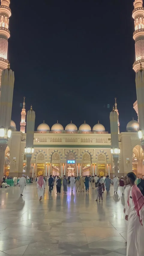 Pilgrims walk through Al Masjid Al Nabawi courtyard at night Stock Footage 323912051