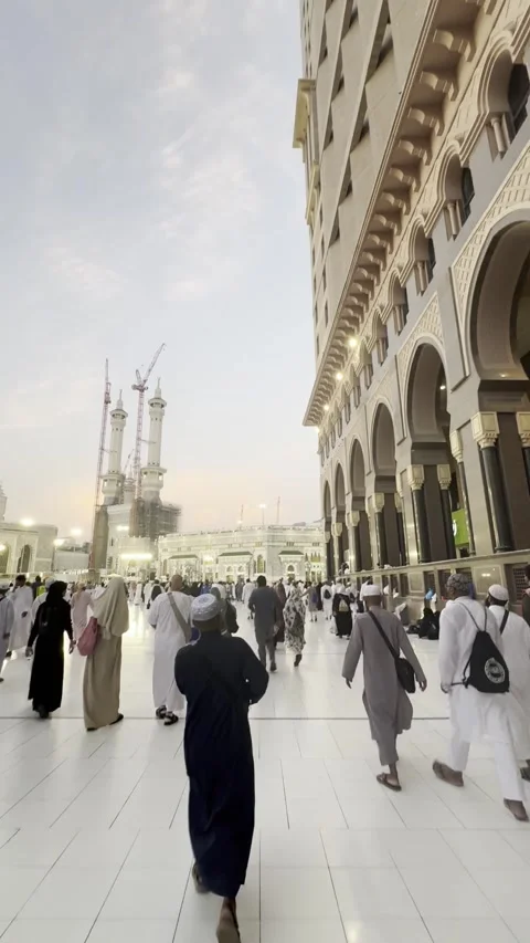 Pilgrims walk through the courtyard area near Masjid al-Haram in Mecca, Saudi Ar Stock Footage 323157202