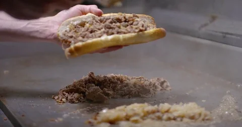 Piling chopped steak and onions into a long roll, creating a Philly cheesesteak Stock Footage 85042996
