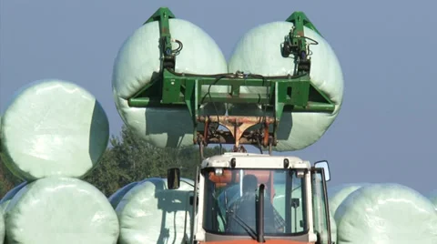 Piling up wrapped hay bales, a combination of hay and silage making Stock Footage 39570351