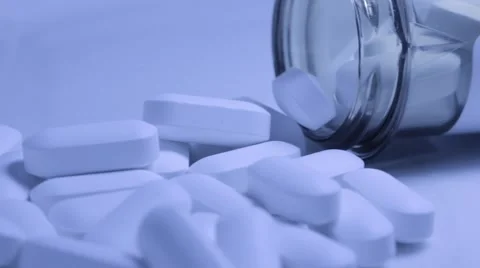 Pill bottle on its side with white tablet pills overflowing Stock Footage 68806179