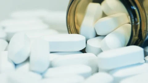 Pill bottle on its side with white tablet pills overflowing Stock Footage 68806821