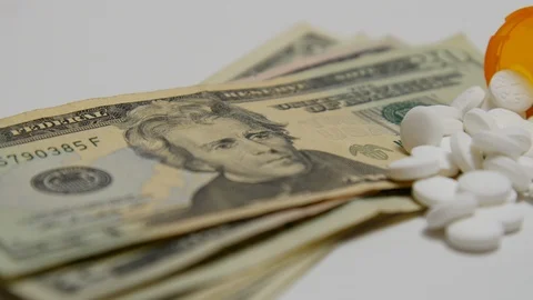 Pill bottle spilled out onto stack of money. Stock Footage 108070440