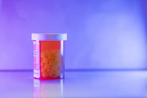 Pill Bottle with White Tablets Under Neon Lights 写真素材