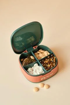 Pill box contains four different types of pills. Pillbox lies on beige Stock Photos
