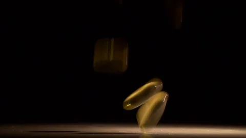 Pill capsule falling and spilling on black surface in slow motion Stock Footage 74769319
