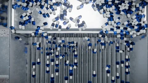 Pill capsules being aligned by a vibrating feeder machine system. Capsules .. Stock-Footage 309514466