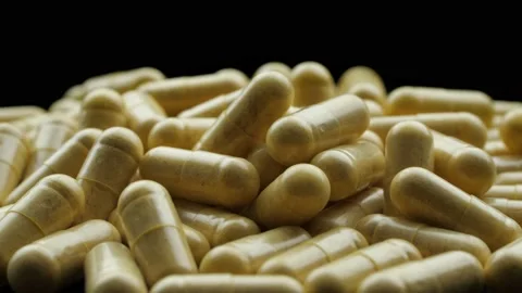 Pill capsules rotate on black background macro Stock Footage 165925588