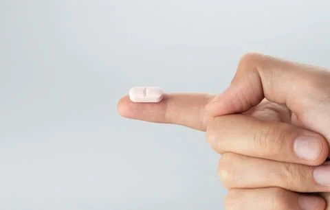 The pill on the finger extra close up. The white pill extra macro view. Stock Photos