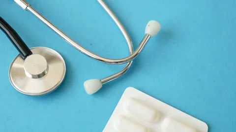 Pill in hand, stethoscope on blue background Video stock 145363837