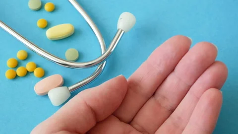 Pill in hand, stethoscope on blue background Video stock 147987381