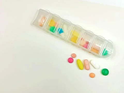 Pill organizer with assorted tablets on white background Foto stock