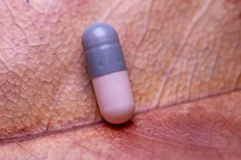 A pill is sitting on a reddish surface Stock-Fotos