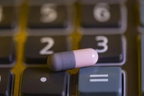 A pill is on top of a calculator Stock-Fotos