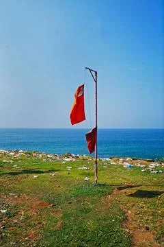 Pillar with two flags on the background of the coast and the sea Stock Photos