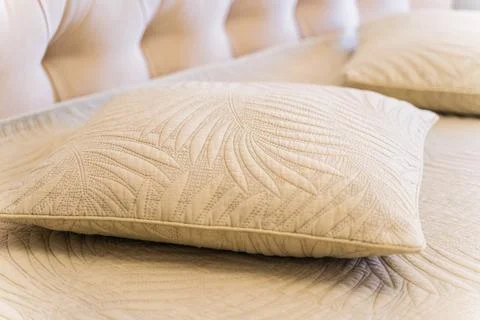 A pillow with a leaf design sits on a bed Stock Photos