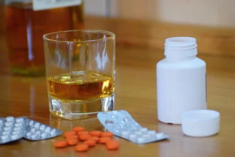 Pills and alcohol on the table, dependency concept Stock Photos
