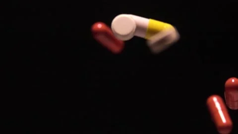 Pills and capsules fall on a black background at a speed of 1000 fps Stock Footage 254520041