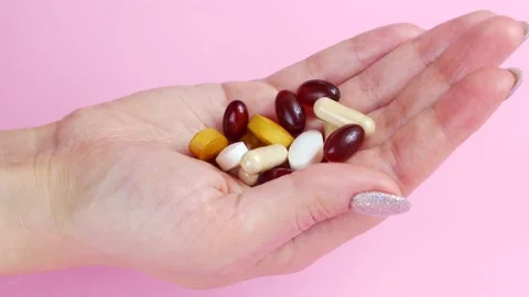 Pills and capsules falling down into the hand on pink background close up Stock Footage 239076192