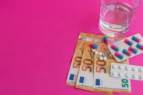 Pills and capsules on fifty euro banknotes and glass of water Stock Photos