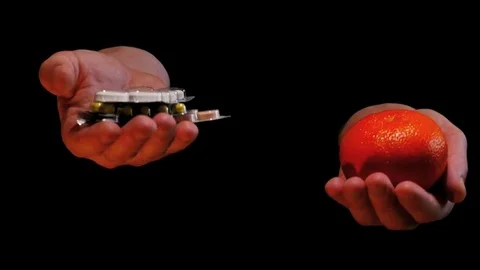 Pills and fruit on balanced hands - chemicals dominance concept Stock Footage 72894214
