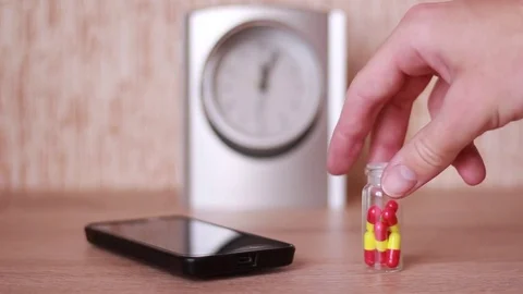 Pills and smartphone in front of clock 動画素材 83030383