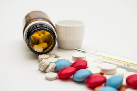 Pills and thermometer Stock Photos