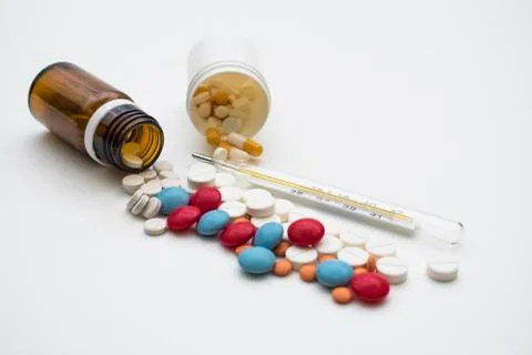Pills and thermometer Stock Photos