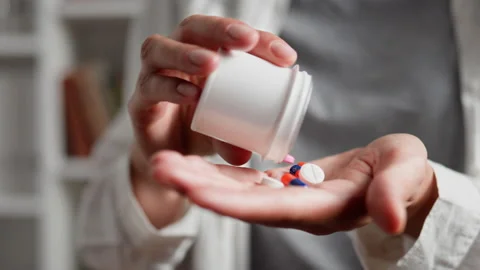 Pills are falling from a vial of a vial into a woman's hand A girl holds bri Stock Footage 218206181