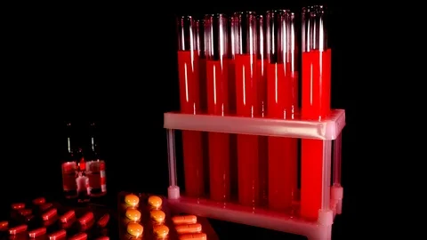 Pills on a background of test tubes with red liquid on a black background Stock Footage 121112827