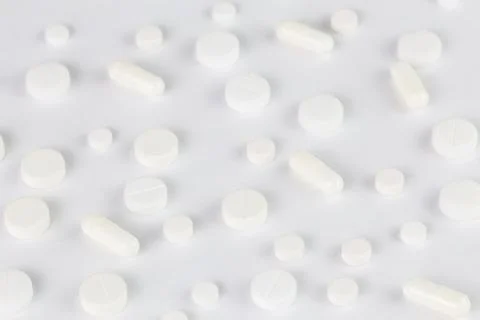Pills background, white tablets spreaded on a white flat surface Stock Photos