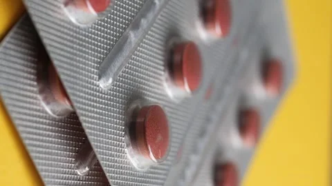 Pills in blister pack packaging close up on yellow background slow motion. Stock Footage 331725763