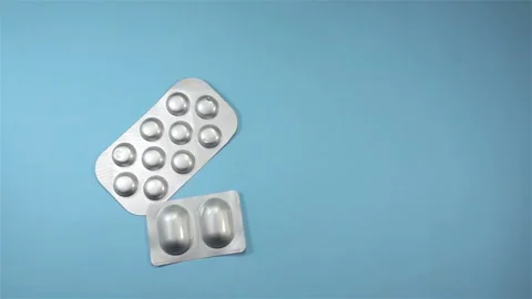 Pills in blisters falling in slow motion on blue Stock Footage 143130573