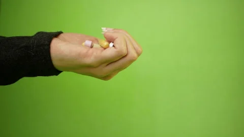 Pills, capsules falling from palm of hand on green background in slow motion. Stock Footage 130817664