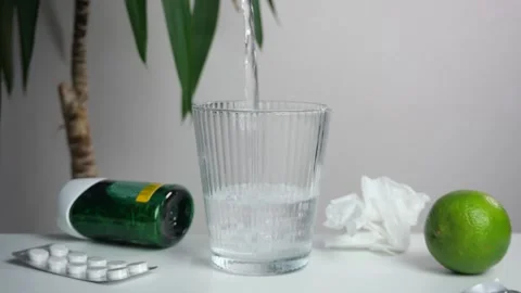 Pills, citrus fruit and an empty glass on the table, into which water is poured. Stock Footage 309883364