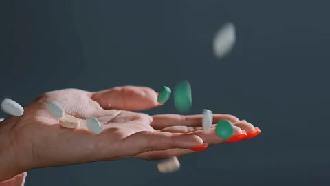 Pills of different colours fall into hand with red manicure Stock Footage 127955074