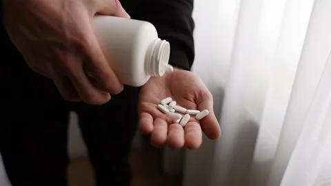 The pills fall from the bottle onto the man's hand in Slow Motion. Stock Footage 231814372