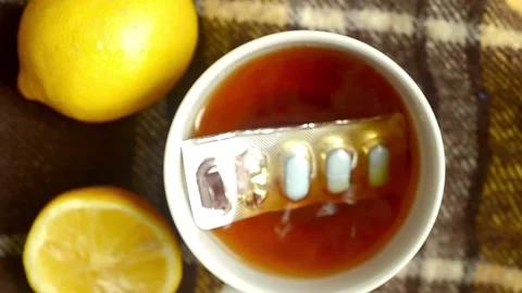 Pills fall into a cup of tea with lemon, close-up. Autumn cold,illness Video stock 155061679