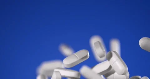 Pills fall in slow motion on blue Stock Footage 344986748